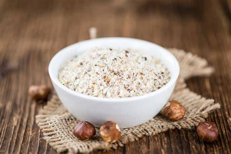 Ganze Haselnüsse und gemahlene Nüsse auf Holztisch