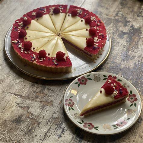 Garnierte Himbeer-Tarte mit weißer Schokolade auf Servierteller