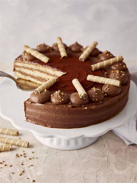 Garnierte Nougat‑Torte mit Haselnusskrokant und Waffelröllchen