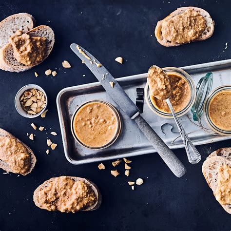 Geöffneter Erdnussbutter-Glas mit Erdnüssen und frischem Brot