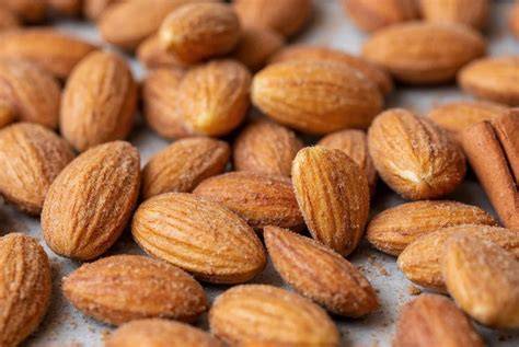 Gebackene Marzipan-Schleifen auf Backblech mit Mandeln bestreut