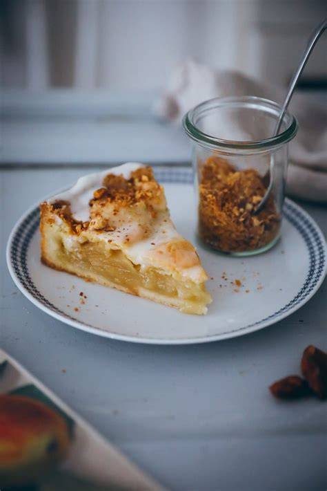 Gedeckter Apfelkuchen mit Ahornsirup-Glasur und gebrannten Mandeln, angeschnitten
