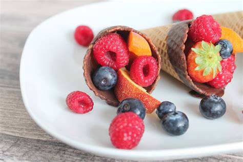 Gefüllte Eiswaffeln mit buntem Obst und Schokoladenrand