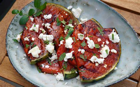 Gegrillte Wassermelone mit Ricotta und frischen Kräutern angerichtet