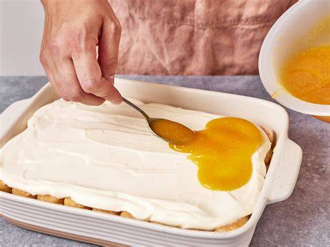 Gelber Maracuja-Fruchtspiegel wird vorsichtig auf Creme gegossen