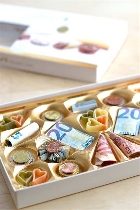 Geldscheine und Münzen kreativ in Pralinenschachtel arrangiert