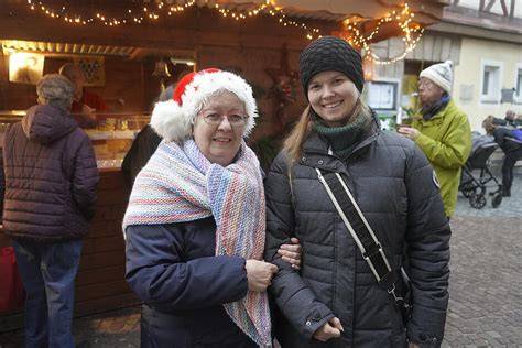 Geschenkübergabe: Lächelnde Person mit Wein-Pralinen-Korb vor festlicher Kulisse