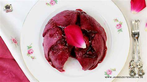 Gestürzter rosa Rosenpudding mit glänzender Beerenkrone und Rosenblättern auf Vintage-Teller