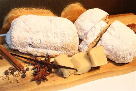 Gestaffelte Anschnitte von Marzipan-Stollen, daneben Butter und Puderzucker