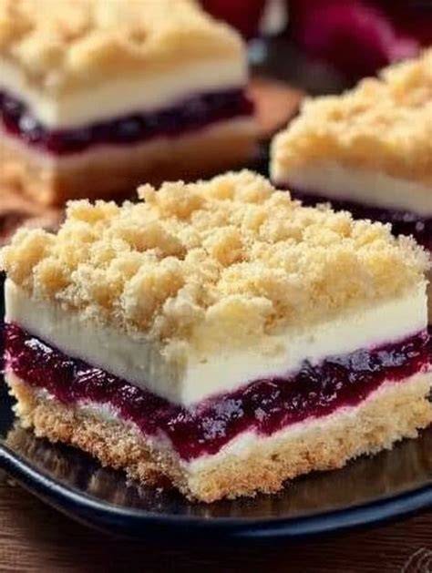 Gestapelte Stücke Käsekuchen mit Kirschen und Streuseln auf einem Holzbrett