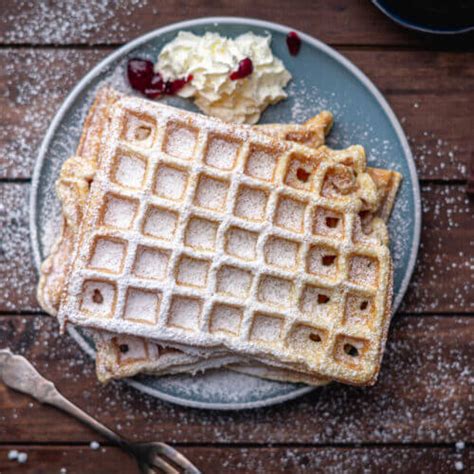 Gestapelte fertige Waffeln, garniert mit Puderzucker und Sahne