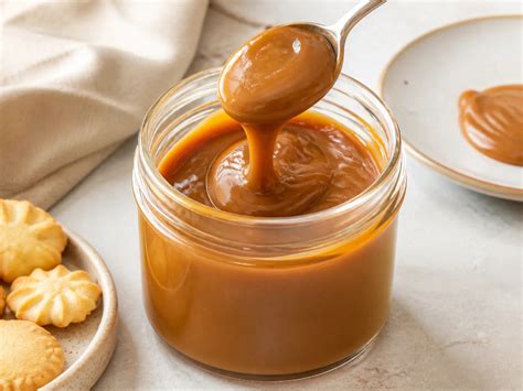 Gläser mit Dulce de Leche und Löffel, daneben Ziegenmilch für Cajeta