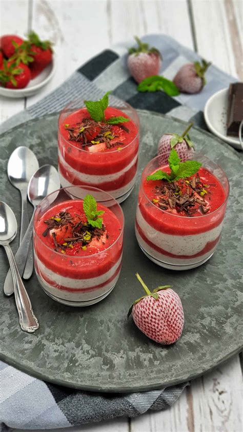 Gläser mit Erdbeer-Käsekuchen, dekoriert mit Minze und weißen Schokoladenraspeln