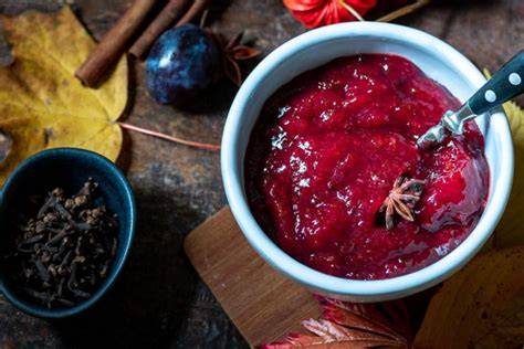 Gläser mit Kaki-Ananas-Marmelade, Vanilleschote und Sternanis arrangiert