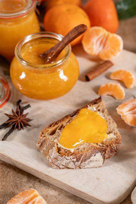 Gläser mit Mandarinenmarmelade und frischen Mandarinen