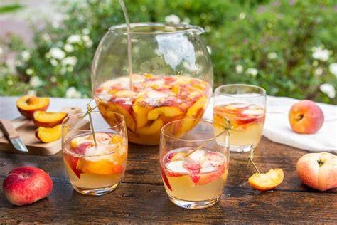 Gläser mit Pfirsich-Prosecco-Marmelade und frischen Pfirsichen, Prosecco-Glas daneben
