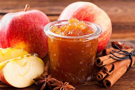 Gläser mit Pflaumen-Nektarinen-Marmelade, Zutaten und Kochutensilien arrangiert