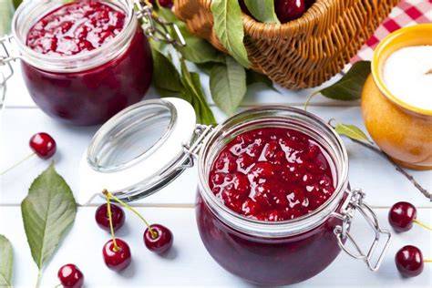 Gläser mit Sauerkirschmarmelade, Zutaten und Thermomix auf der Arbeitsfläche