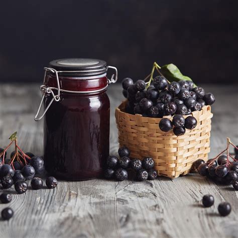 Gläser mit dunkler Aronia-Marmelade auf rustikalem Holz