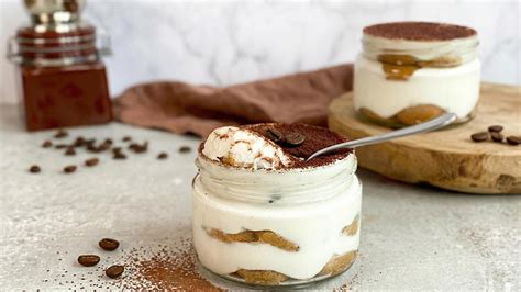 Gläser mit fertig geschichtetem Tiramisu und Kakaopulver bestäubt