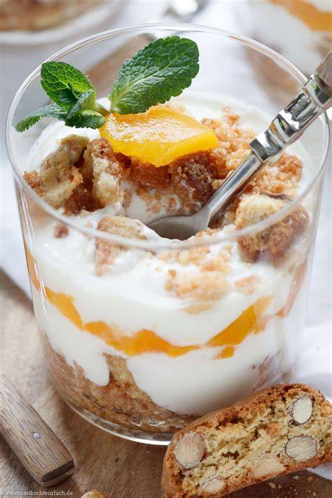 Gläser mit geschichtetem Joghurt Cantuccini Dessert und Pfirsichen