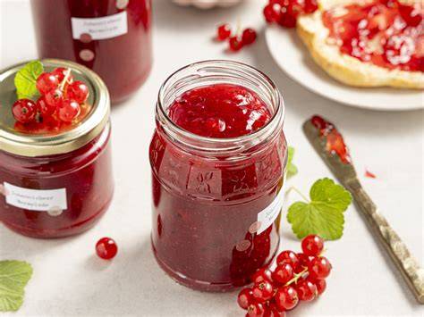 Gläser mit leuchtend roter Johannisbeermarmelade auf Holztisch