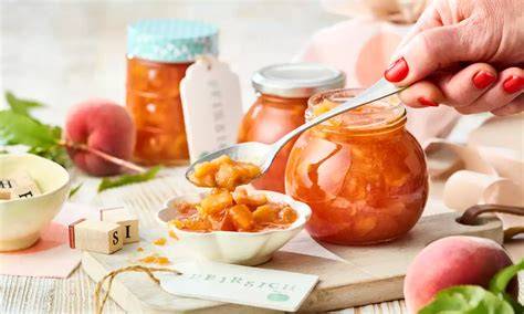 Gläser mit selbstgemachter Pfirsichmarmelade und Basilikum