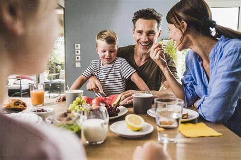 Glückliche Familie beim Genießen einer Oreo-Torte, Kinder und Erwachsene rund um den Tisch