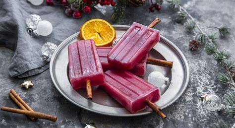 Glühwein-Eis am Stiel auf Teller mit Zimtstangen