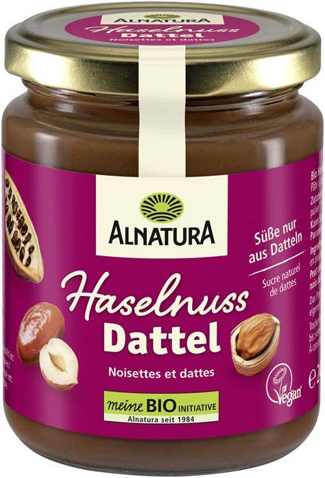 Glas Alnatura Schoko Dattel Aufstrich neben Haselnüssen, Datteln und Kakaopulver