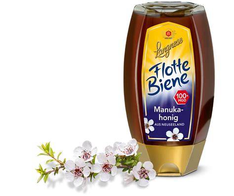 Glas Manuka-Honig mit Honiglöffel und Blüten des Manuka-Strauchs