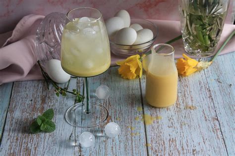 Glas frischer Eierlikör und Zutaten auf Küchenbrett