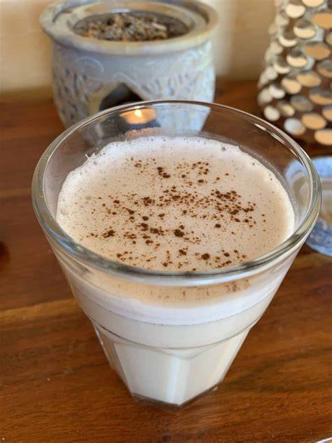 Glas heiße Milch mit Zimt und Honig, garniert mit Muskat