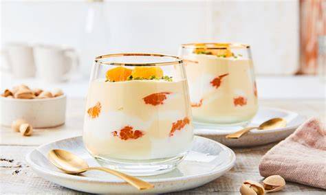 Glas mit Aprikosen-Ricotta-Joghurt-Dessert, garniert mit frischen Aprikosenscheiben