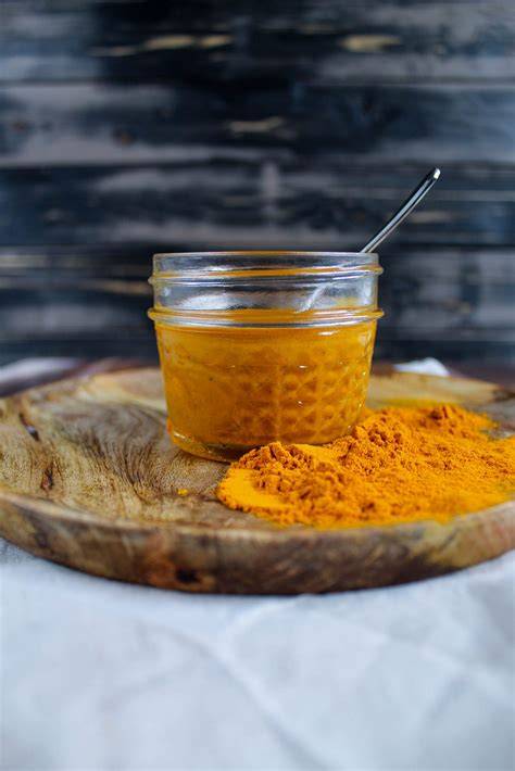 Glas mit Kurkuma-Honig Paste und Löffel