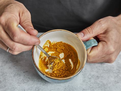 Glas mit Kurkuma-Honig-Paste in einem Löffel