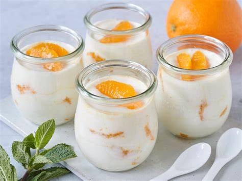 Glas mit Orangen-Joghurt-Dessert und gerösteten Mandeln