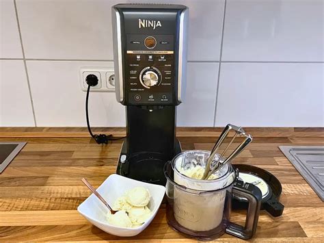 Glas mit Schoko-Milchshake, Zutaten und Ninja Creami auf der Arbeitsfläche