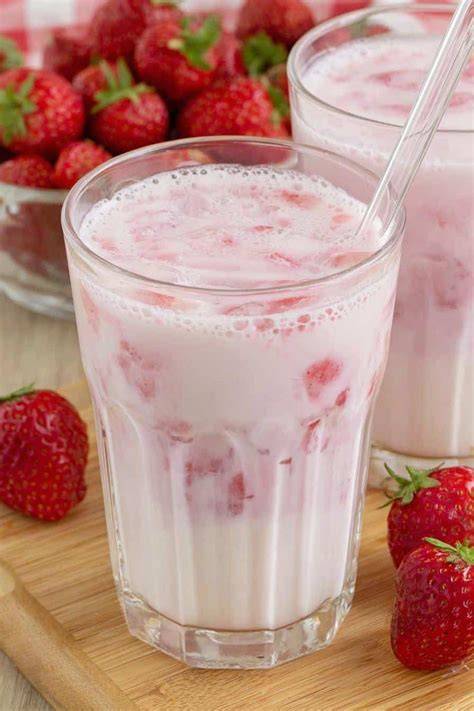 Glas mit cremiger Erdbeermilch und frischen Erdbeeren garniert
