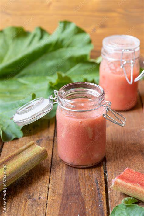 Glas mit frisch gekochter Rhabarber-Marzipan-Marmelade auf Frühstückstisch