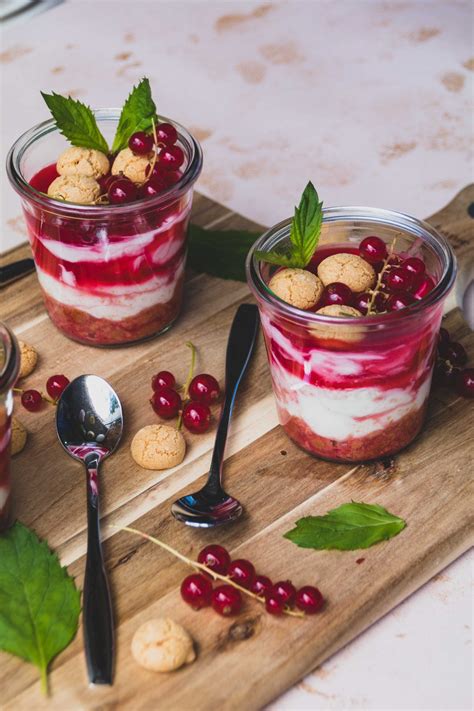 Glas mit schnellem Johannisbeer-Dessert, garniert mit Baiser und Amarettini