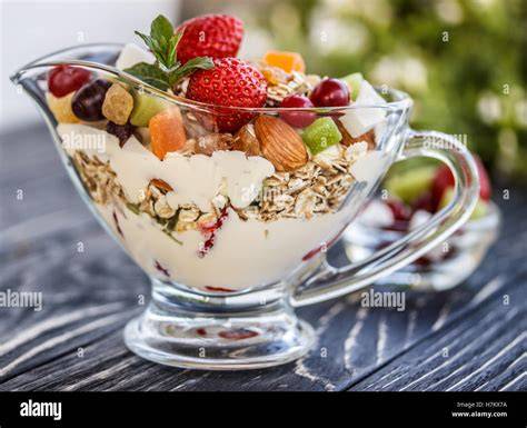 Glasschüssel mit geschichtetem Müsli-Dessert und Kirschen