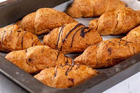 Goldbraune, aufgebrochene Croissants auf Backblech