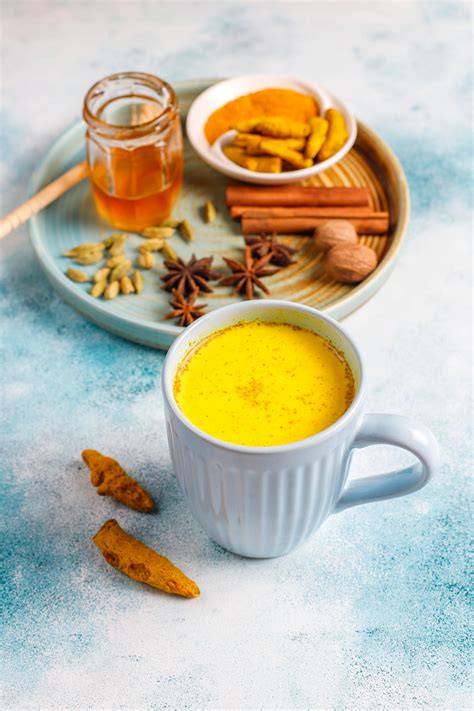 Goldene Milch in Tasse mit Kurkuma und Pfeffer daneben