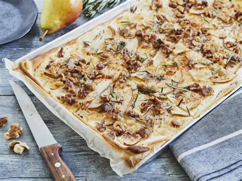 Gorgonzola, Birnenscheiben und Walnüsse auf Flammkuchen vor dem Backen