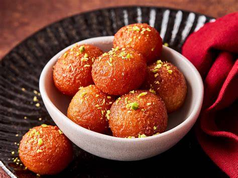 Gulab Jamun auf Teller mit Pistazien und Sirup