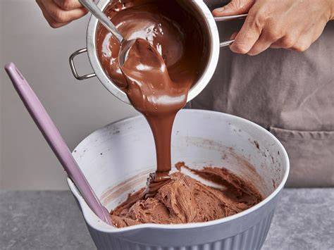 Guss aus Zartbitterkuvertüre wird über Kuchen gegossen