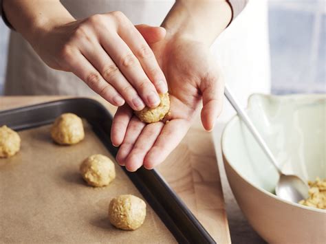 Hände formen Kugeln aus schokoladigem Teig, bereit zum Wälzen in Zucker