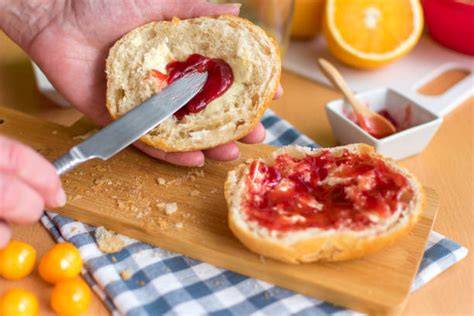 Halbes Brötchen mit Marmelade auf Teller