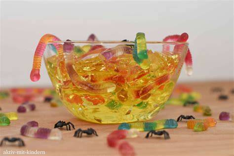 Halloween-Götterspeise mit Fruchtgummi-Würmern dekoriert in Glasschale